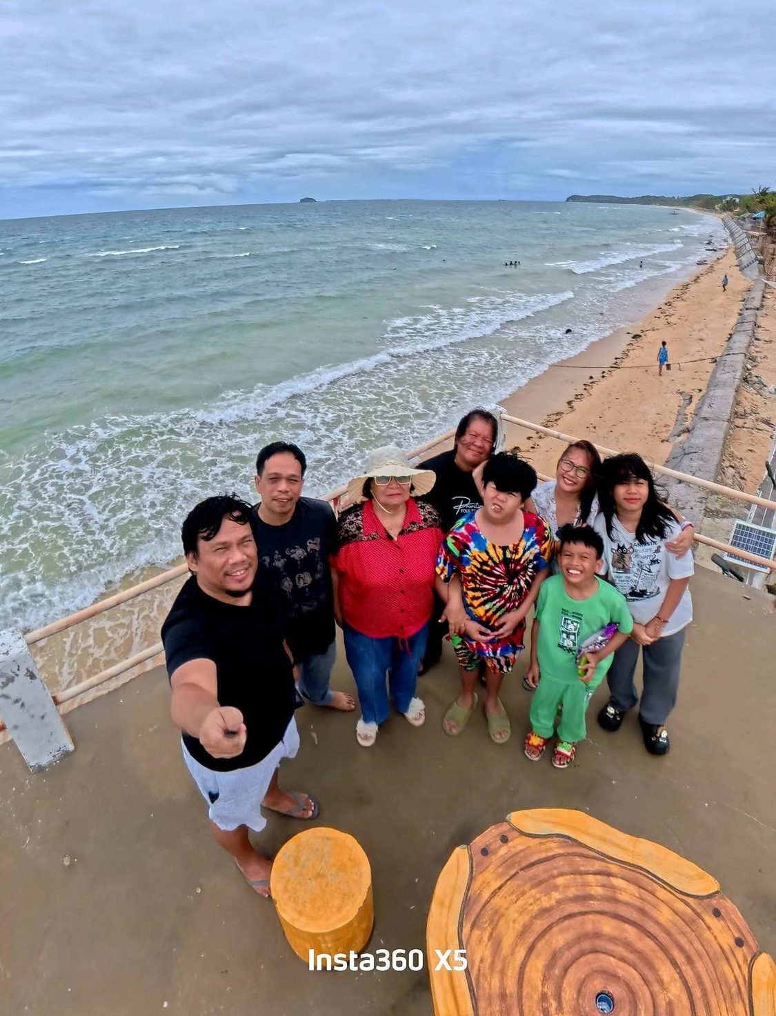 Oscar Perocho Jr. and his family together on a seaside viewing deck above a wide beach in northern Cebu.